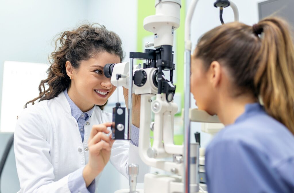 A smiling female optometrist examines a female patient's eyes for a dry eye diagnosis.