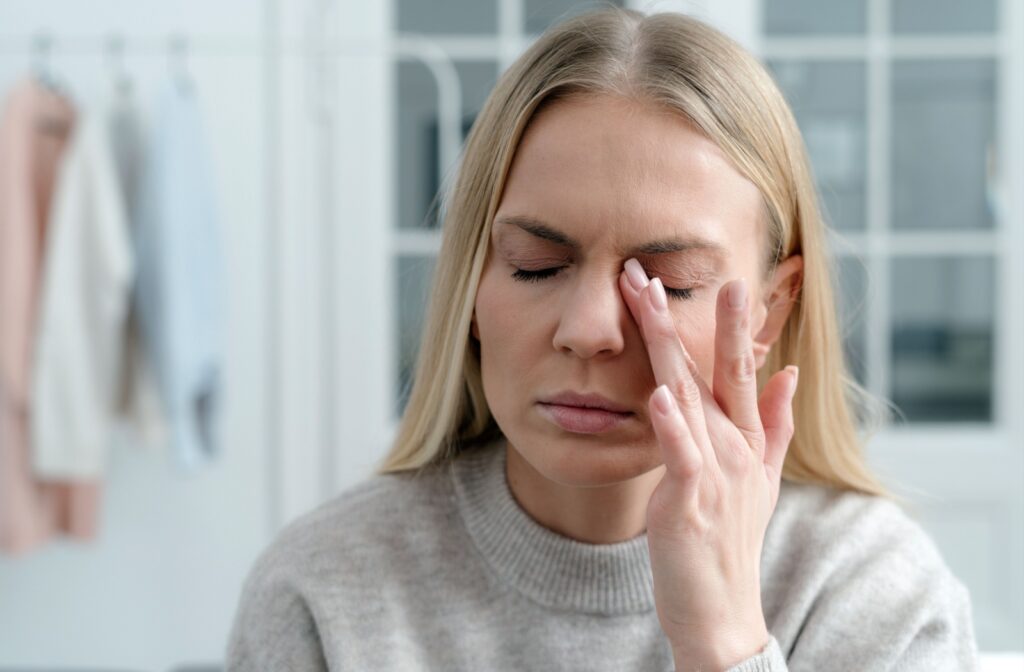 A woman rubs her eyes with her left hand to find relief from dry eyes.
