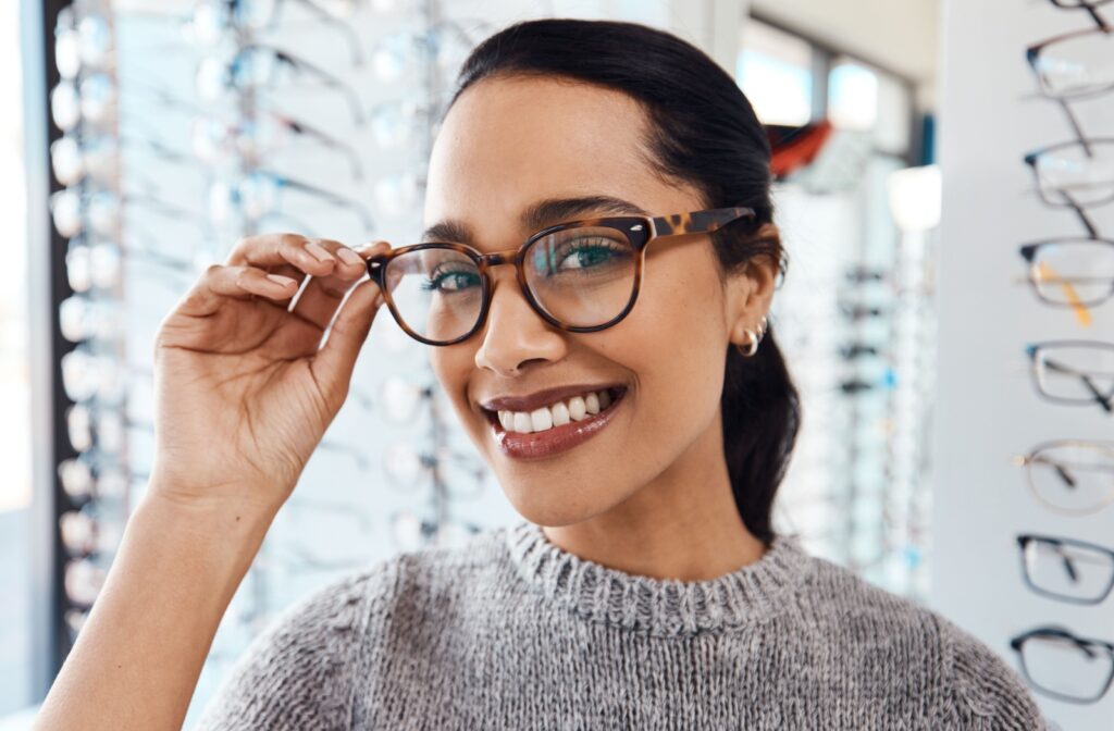 A woman trying on a pair of brown glasses while choosing from eyeglasses at her local optometry.