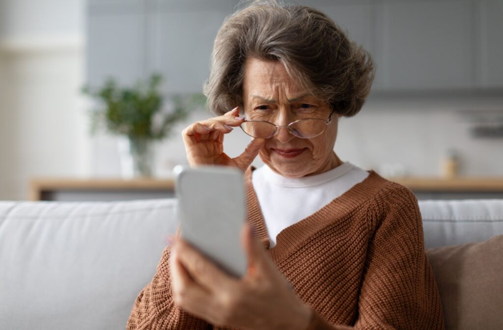 A mature individual adjusts their glasses and squints because of blurry vision caused by dry eyes.