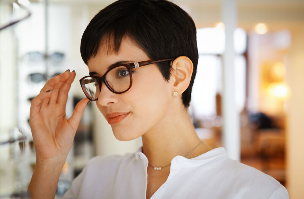A smiling adult tries on glasses frames in a showroom.