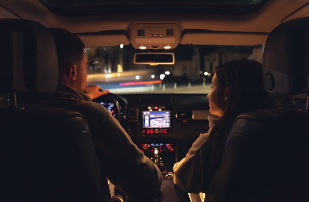 Two people in a care driving at night.