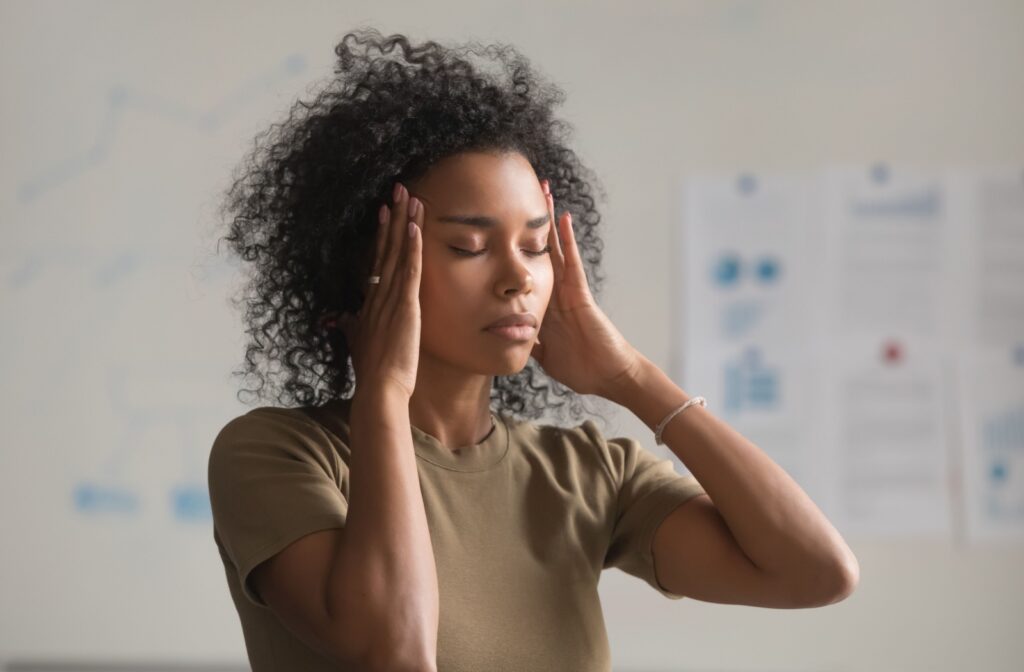 Woman with her hands up to her temples to sooth a headache