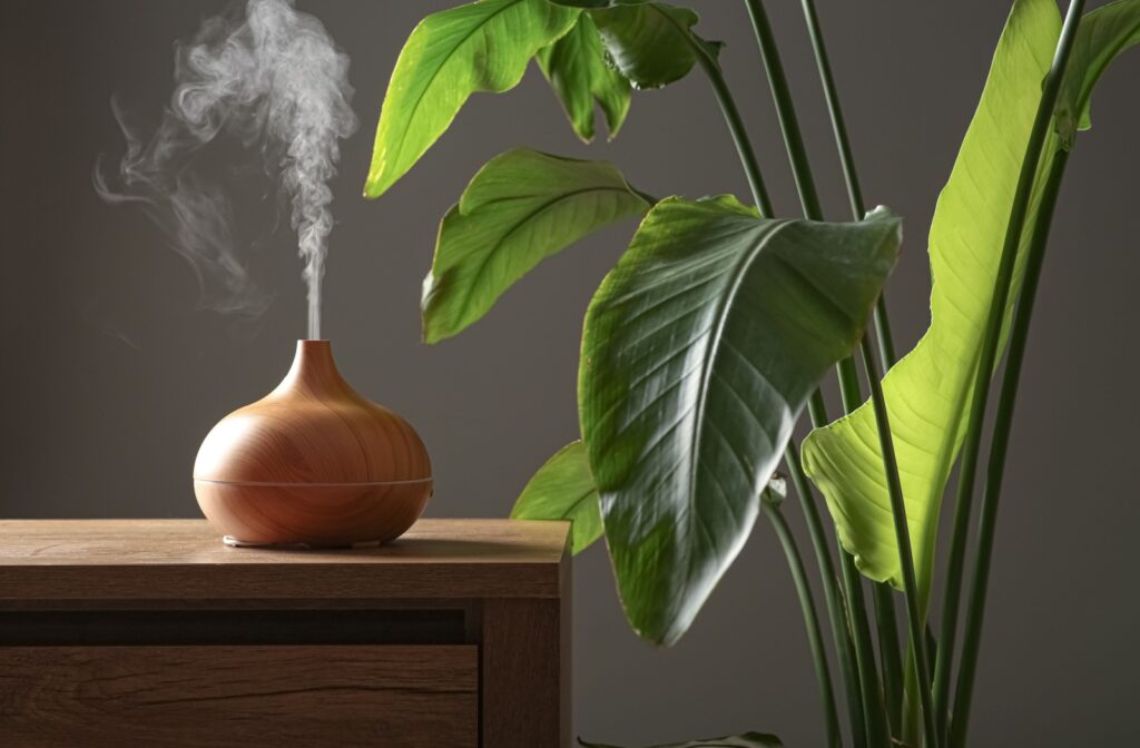 A wood humidifier sits on a table next to a plant in front of a gray background