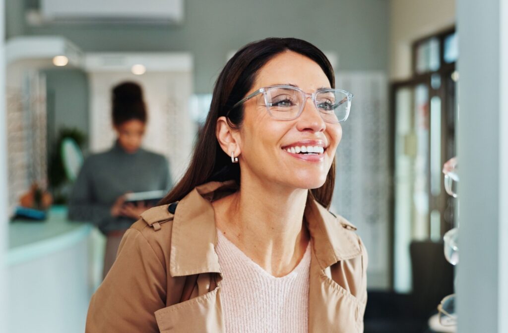 A person wearing a translucent pair of eyeglasses looks in the mirror smiling