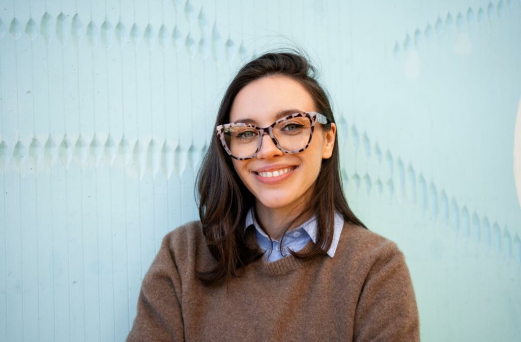 A person wearing trendy glasses in front of a blue background